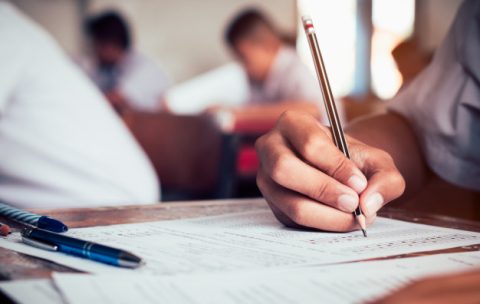 close-up-student-holding-pencil-writing-final-exam-examination-room-study-classroom-vintage-style_73622-242